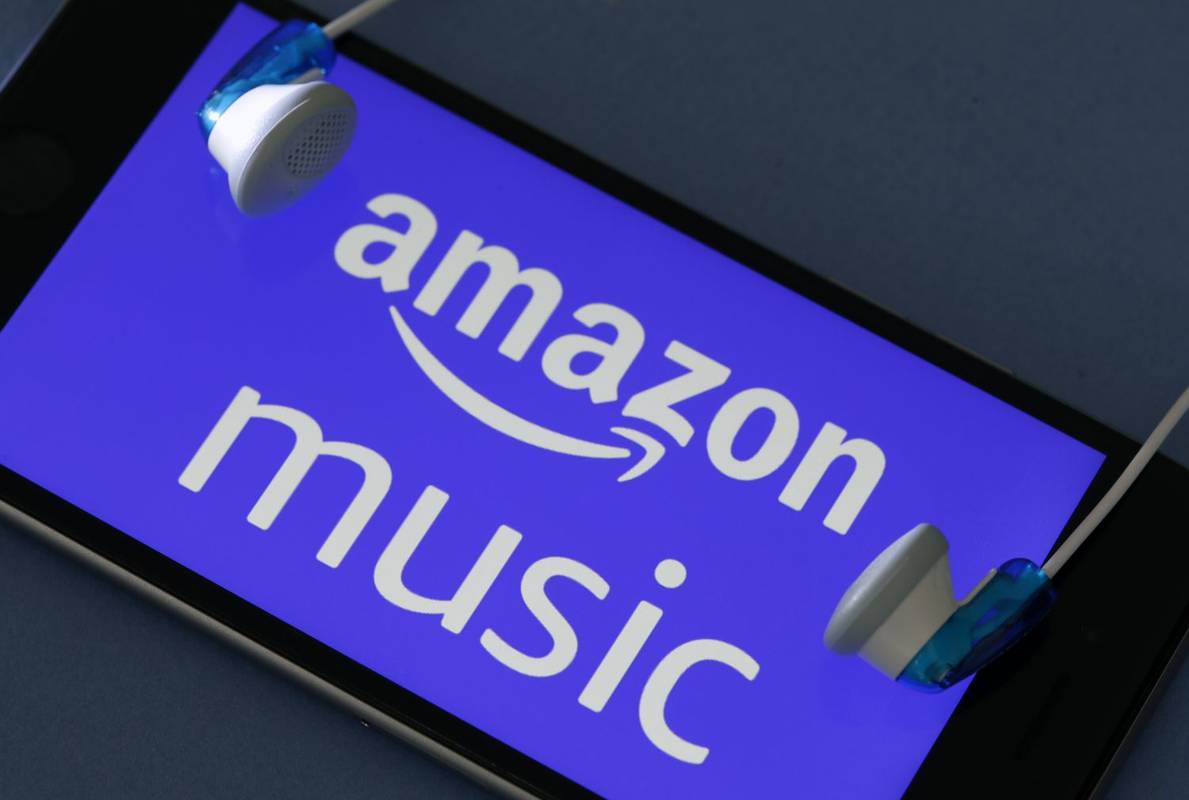 Amazon Music 음악 다운로드 서비스 로고가 표시된 스마트폰 주변의 헤드폰