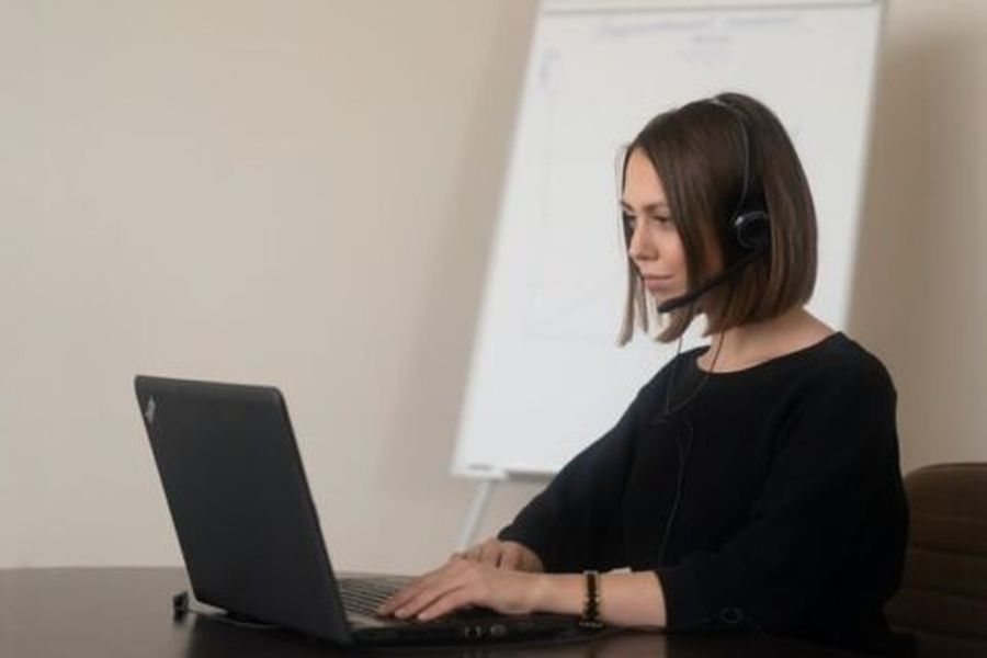 Tyttö käyttää kannettavan tietokoneen kuulokkeita ja kuinka käyttää kuulokemikrofonia tietokoneessa