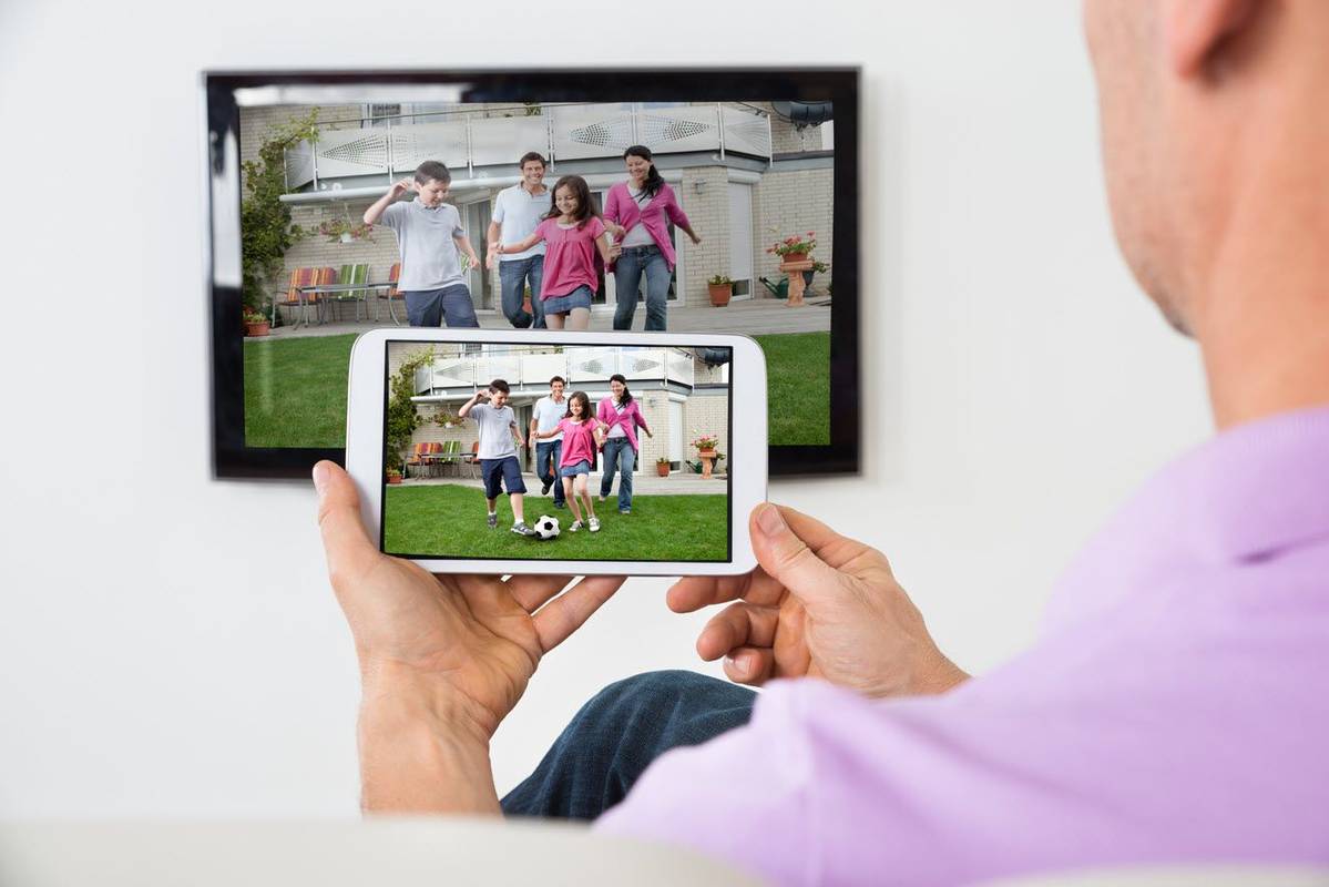Muž zrcadlení iPad mini do televize pro zobrazení domácích filmů.
