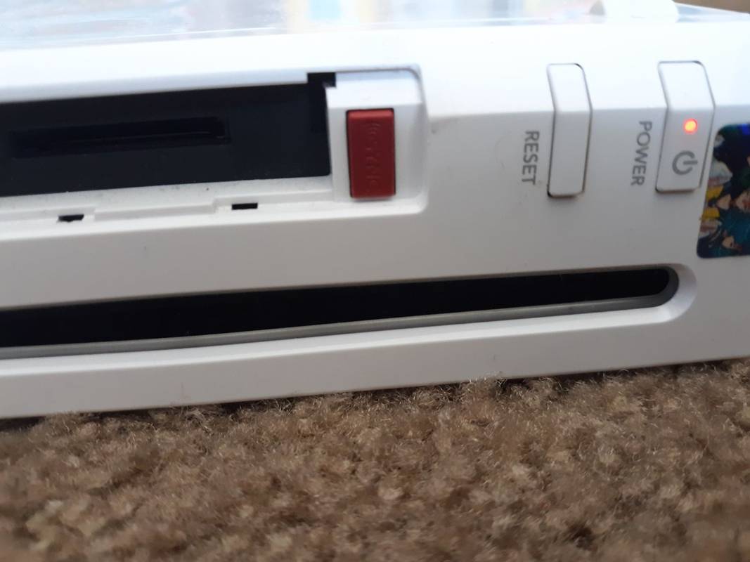 Nút đồng bộ màu đỏ nằm dưới nắp khe cắm thẻ nhớ ở mặt trước của máy Wii.