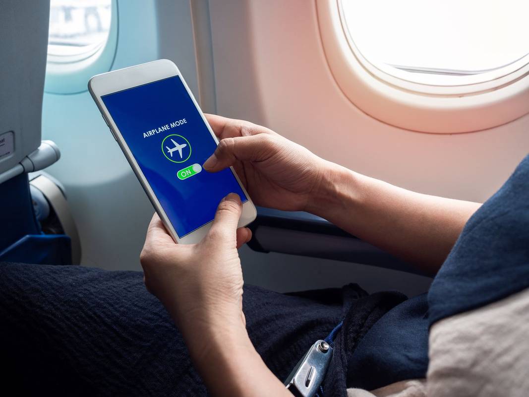 Une personne activant le mode Avion sur son smartphone dans un avion.