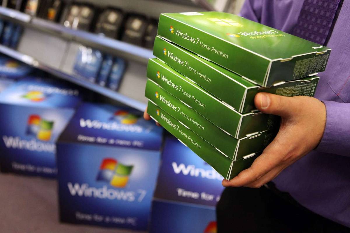 Mies kantaa Windows 7:n myyntipakkauksia